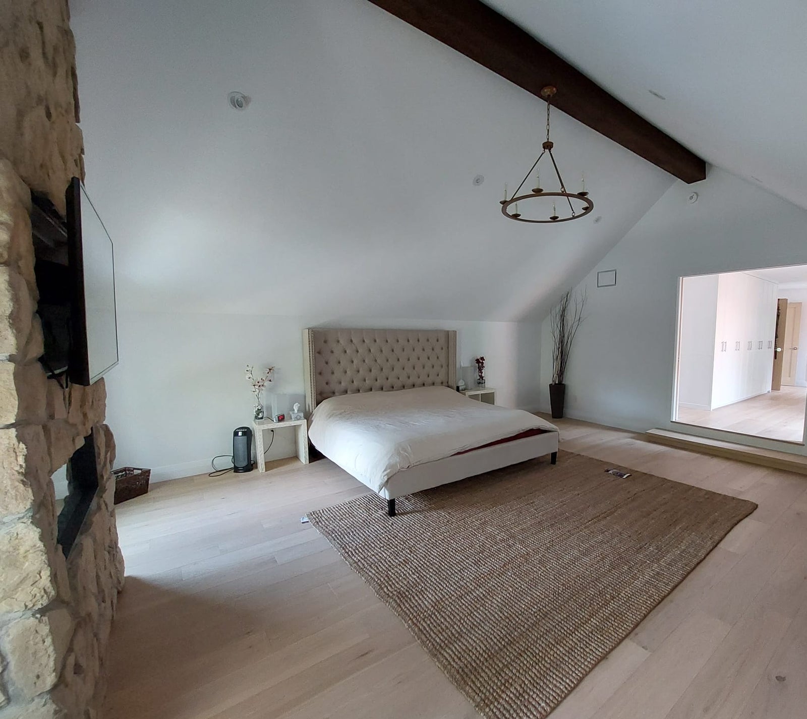 Modern bedroom with a bed, rug, and stone wall.